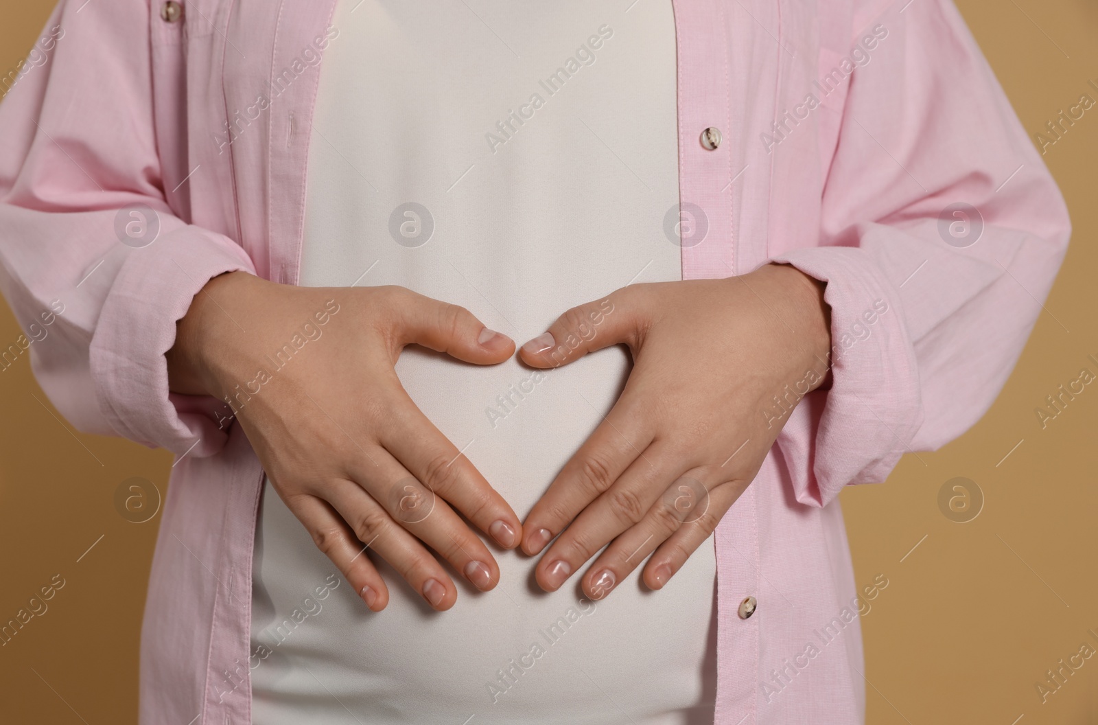 Photo of Pregnant woman on light brown background, closeup