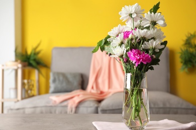 Photo of Beautiful bouquet of Chrysanthemum flowers on grey table indoors, space for text. Interior design
