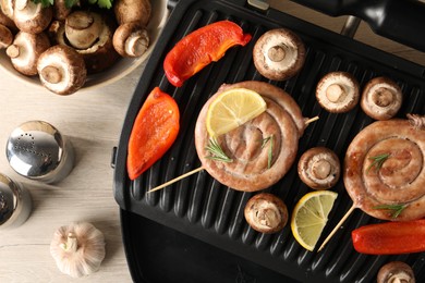 Flat lay composition with electric grill and homemade sausages on wooden table