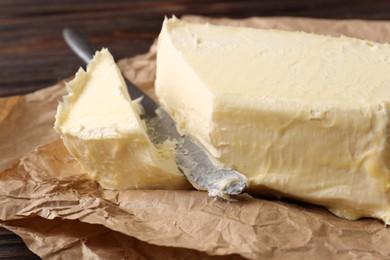 Photo of Tasty homemade butter and knife on parchment, closeup