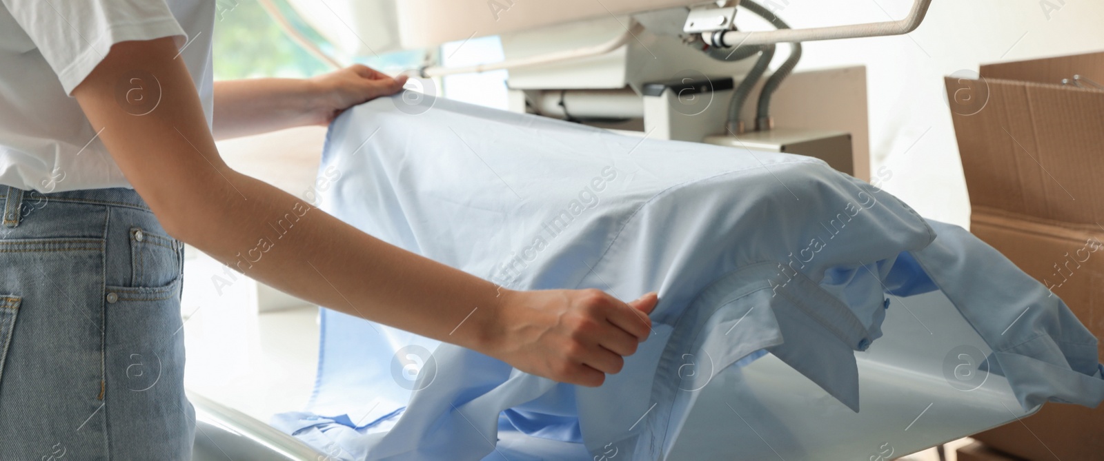 Image of Closeup view of female worker using ironing press, banner design. Dry-cleaning service