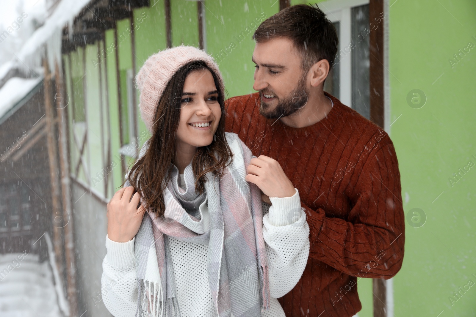 Photo of Lovely couple wearing warm sweaters outdoors on snowy day. Winter season