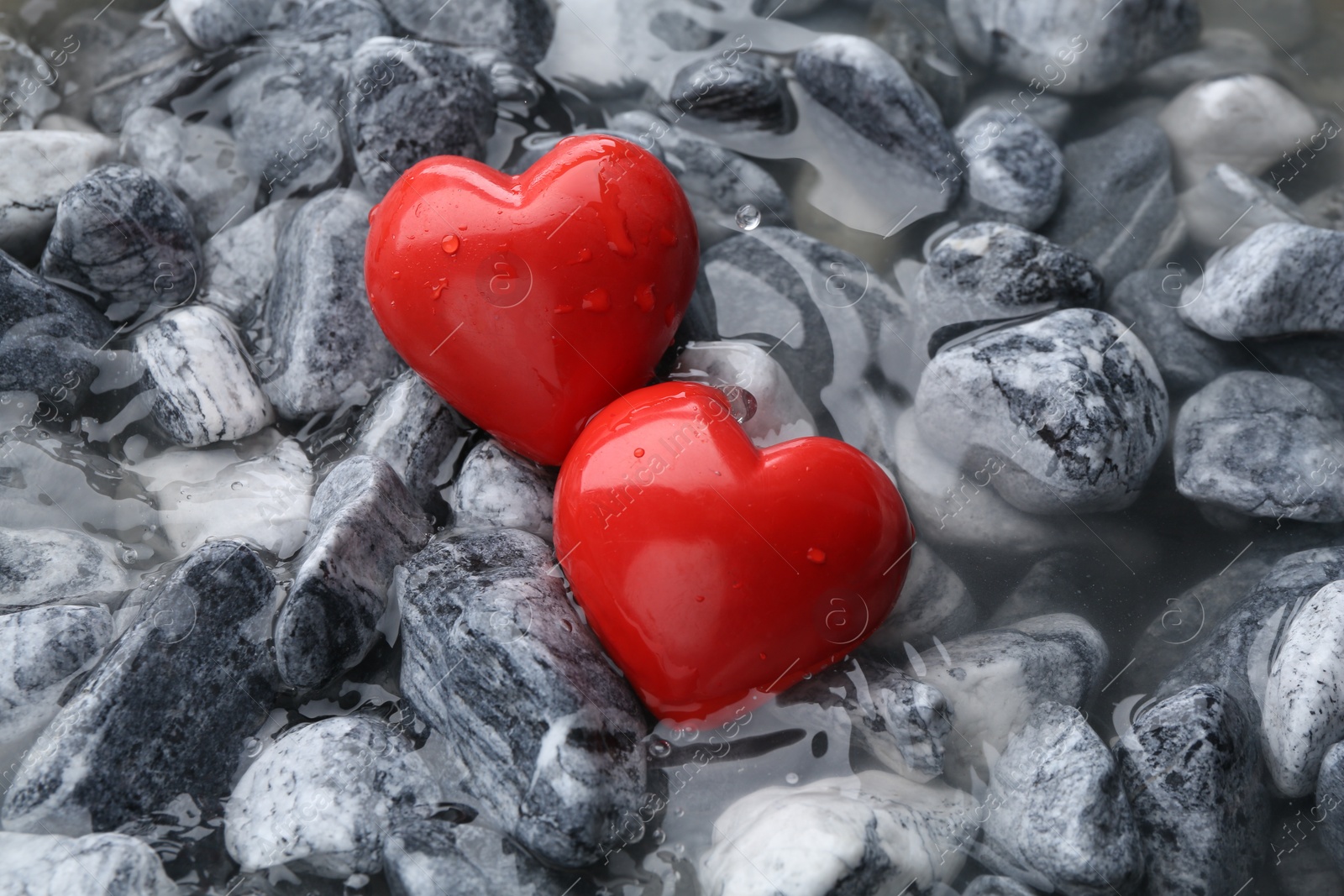 Photo of Red decorative hearts on stones and water