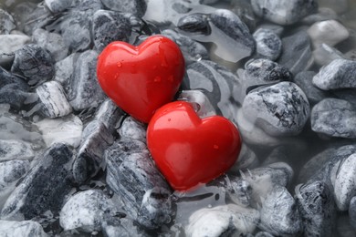 Photo of Red decorative hearts on stones and water