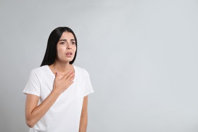 Photo of Young woman suffering from breathing problem on light background. Space for text