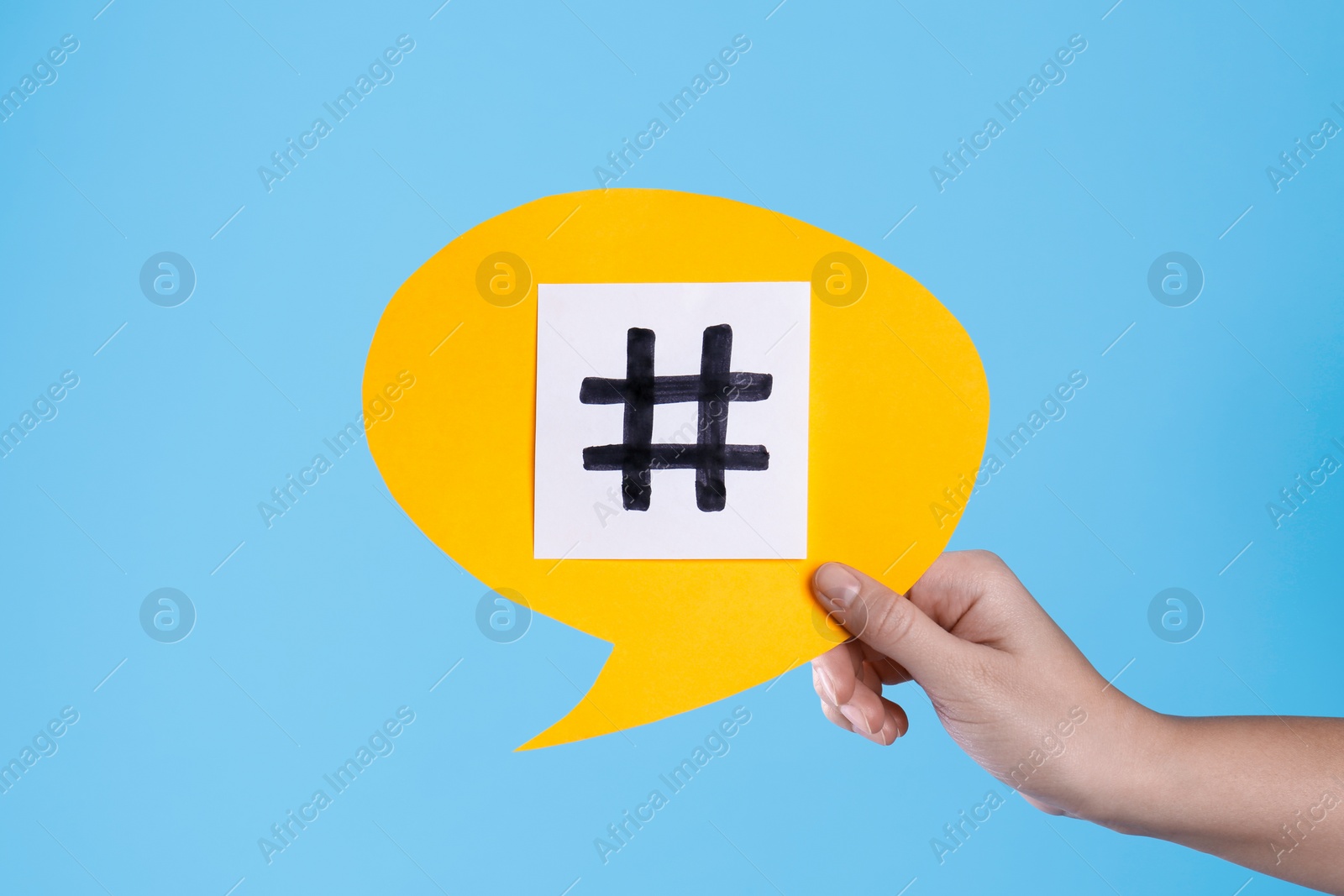 Photo of Woman holding yellow paper speech bubble with hashtag symbol on turquoise background, closeup