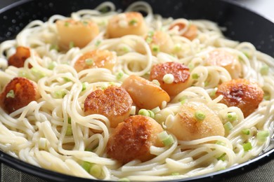 Delicious scallop pasta with green onion on table, closeup