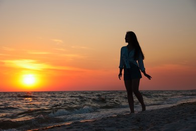 Photo of Girl on sandy beach near sea at sunset