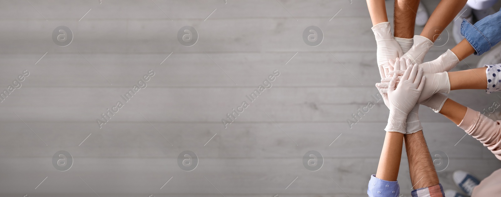 Image of People in white medical gloves stacking hands indoors, top view. Banner design with space for text 