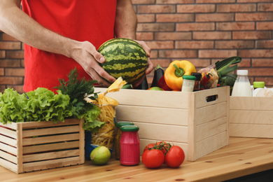 Photo of Man with fresh products at table indoors, closeup. Food delivery service