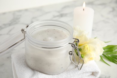 Photo of Jar of salt scrub, freesia flowers and towel on white marble table