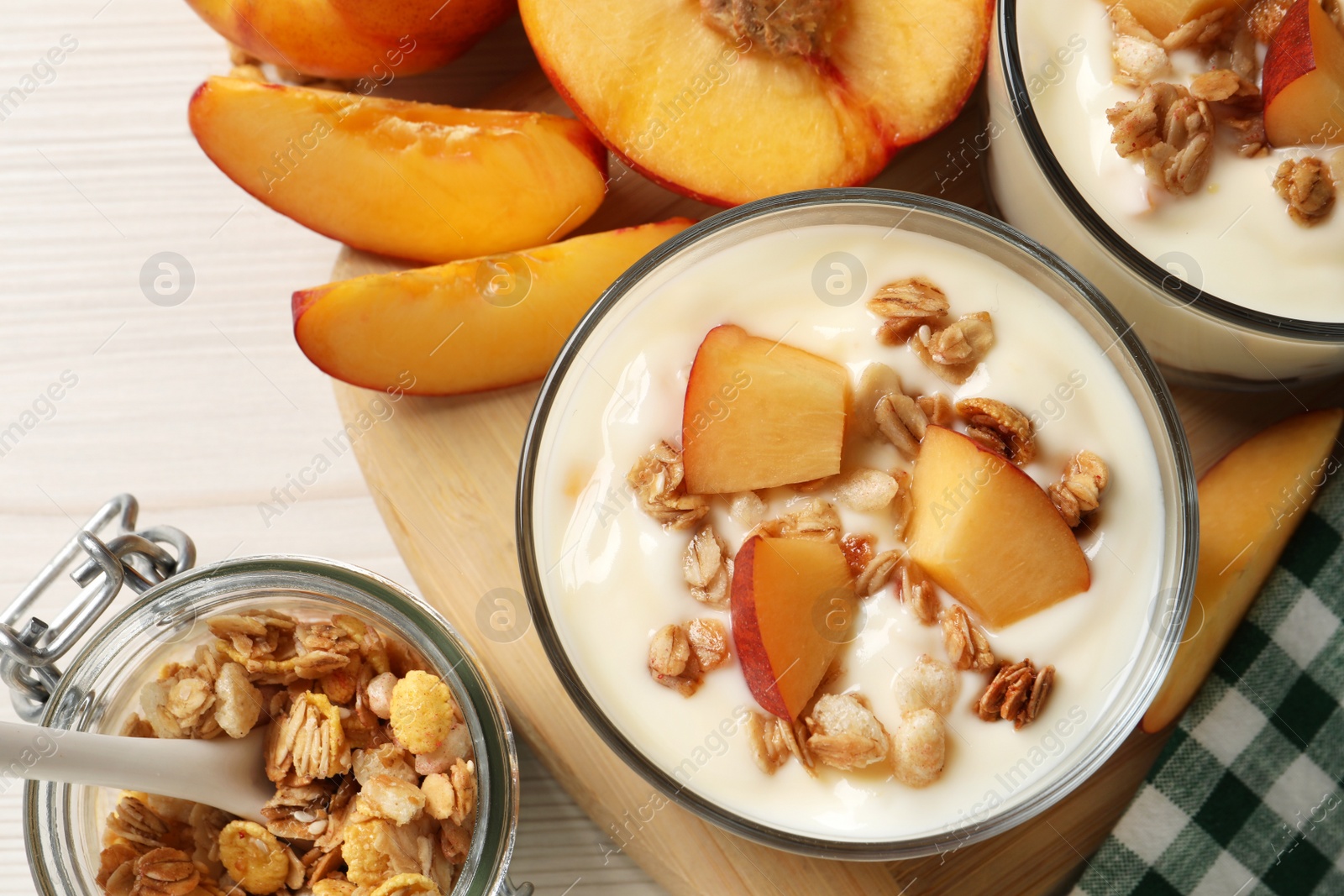 Photo of Delicious yogurt with fresh peach and granola on white table, flat lay