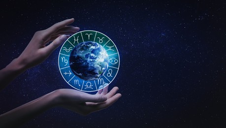 Image of Woman holding illustration of Earth with zodiac wheel around it in open space, closeup
