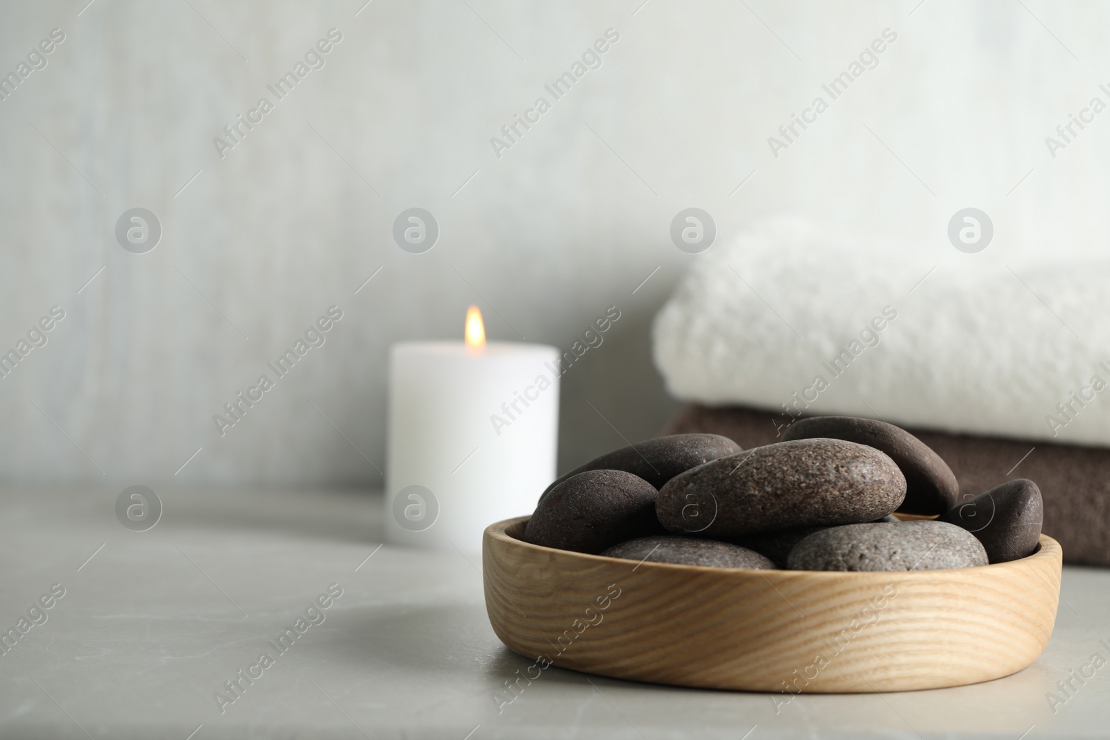 Photo of Spa stones in wooden tray on light table. Space for text