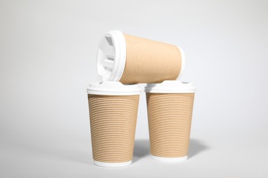 Paper cups with white lids on light gray background. Coffee to go