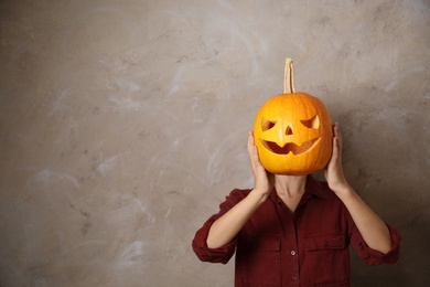 Woman with pumpkin head against beige background, space for text. Jack lantern - traditional Halloween decor