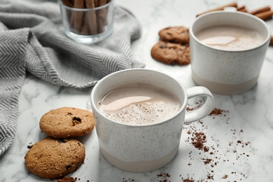 Photo of Cookies and cups with delicious hot cocoa drink on table