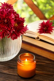 Photo of Beautiful pink chrysanthemum flowers, burning candle and books on wooden table