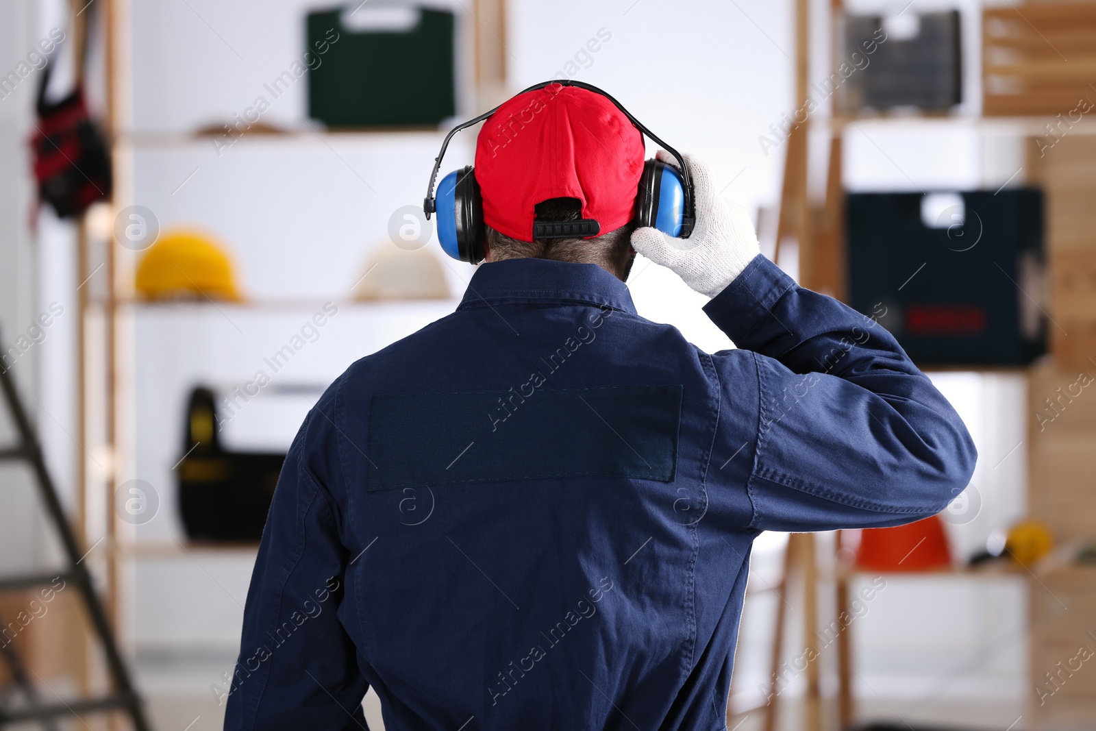 Photo of Worker wearing safety headphones indoors, back view. Hearing protection device