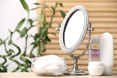 Photo of Cotton pads, mirror and cosmetic products on table