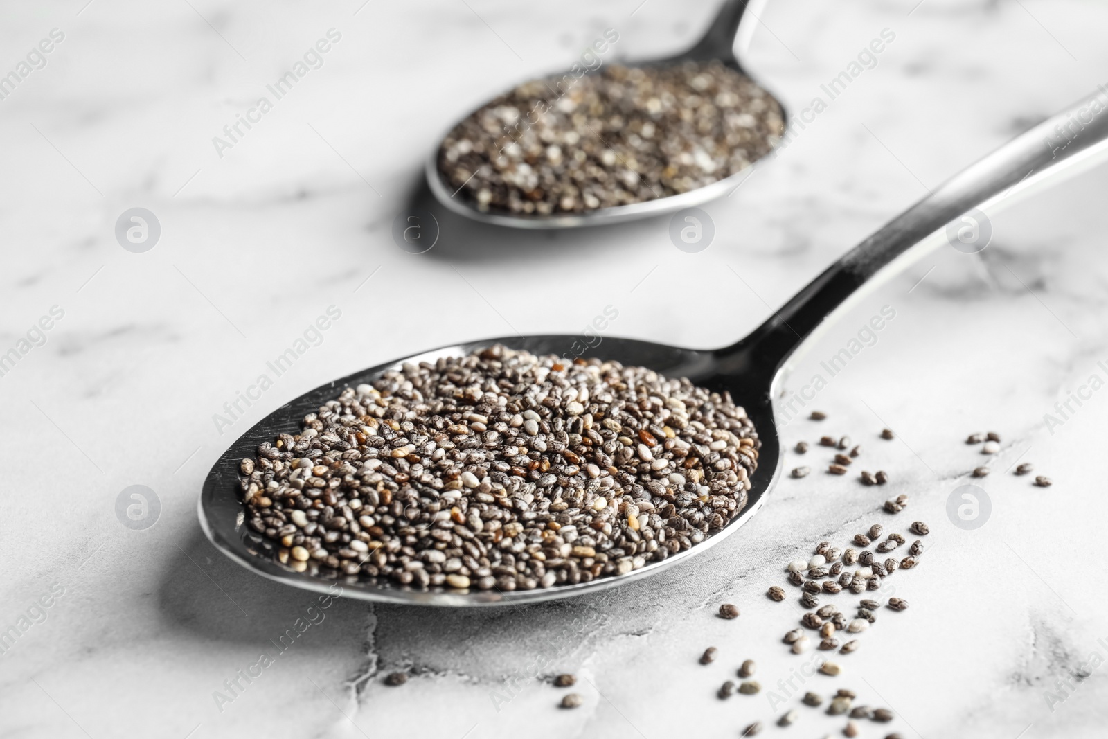 Photo of Spoon with chia seeds on marble background, closeup