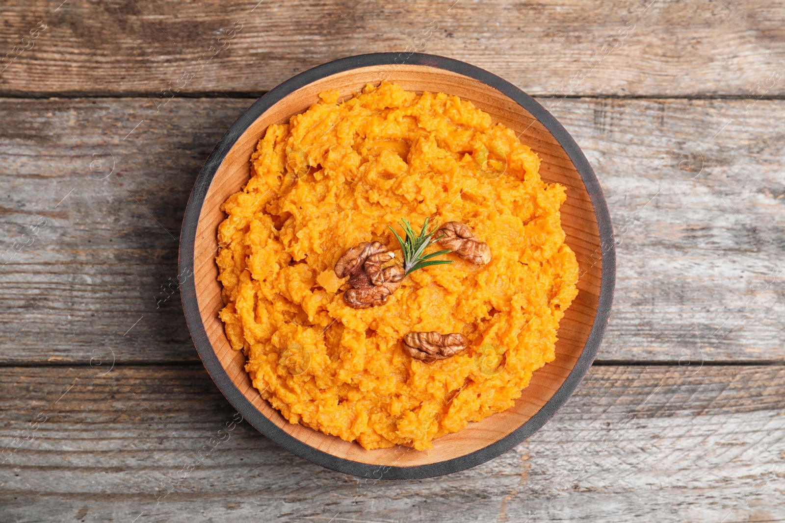 Photo of Bowl with mashed sweet potatoes on wooden table, top view