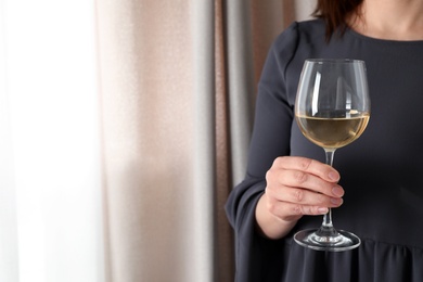 Photo of Woman with glass of wine indoors, closeup. Space for text