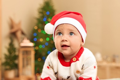 Photo of Cute little baby in Christmas sweater and Santa hat at home. Winter holiday