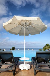 Photo of Chaise longues and beach parasol near infinity pool at resort