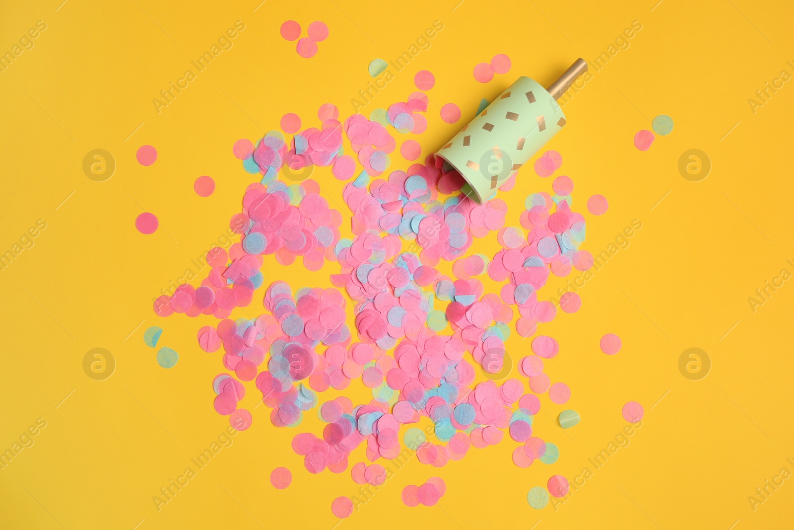 Photo of Party popper with bright confetti on orange background, flat lay