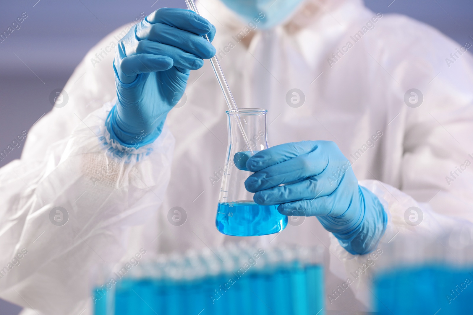 Photo of Scientist taking sample of light blue liquid on grey background, closeup