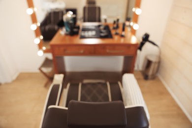 Photo of Blurred viewstylish hairdresser's workplace with armchair and professional tools in barbershop