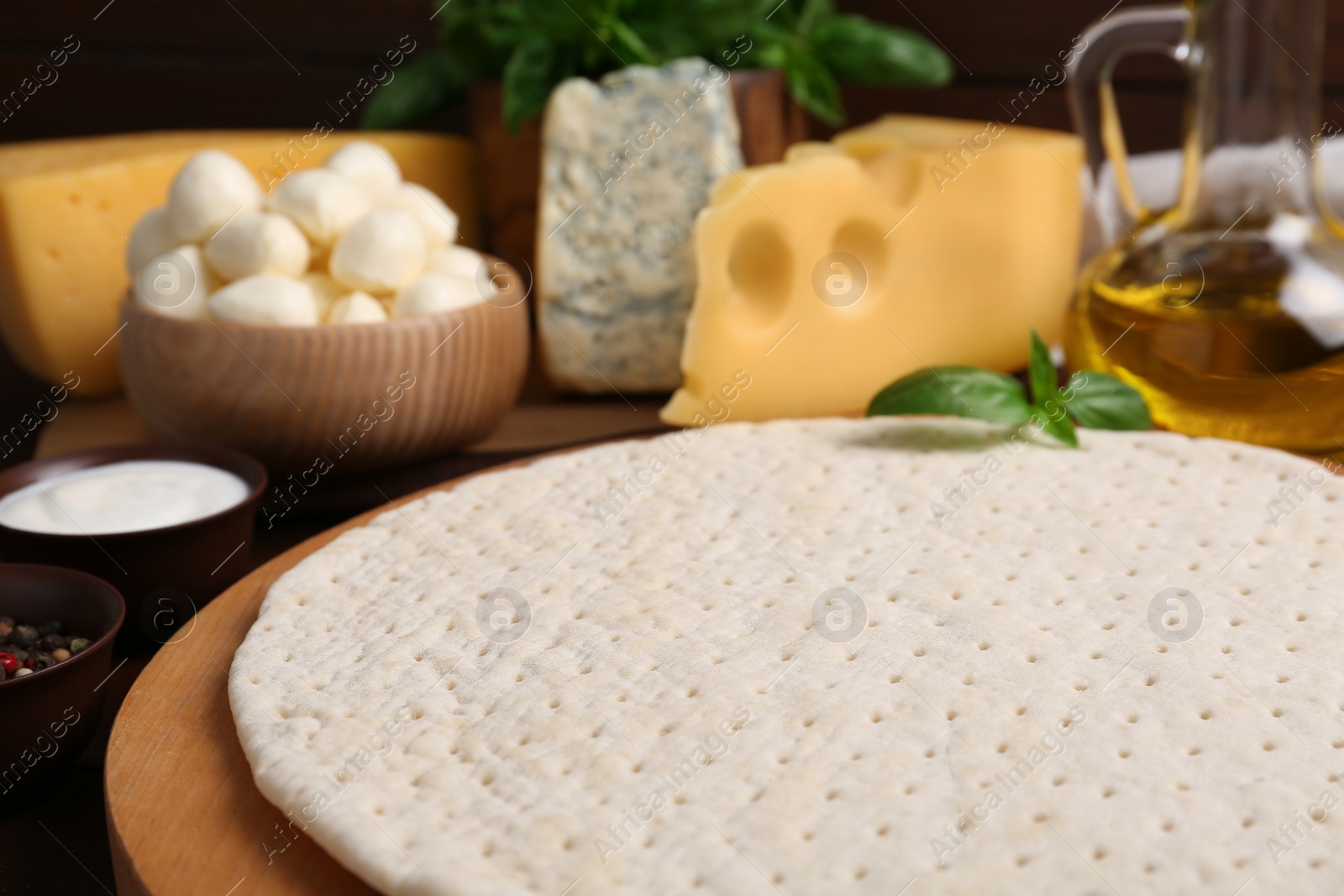 Photo of Pizza crust and fresh ingredients on table, closeup