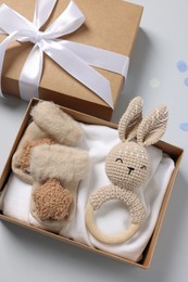 Different baby accessories in box and confetti on light grey background, flat lay