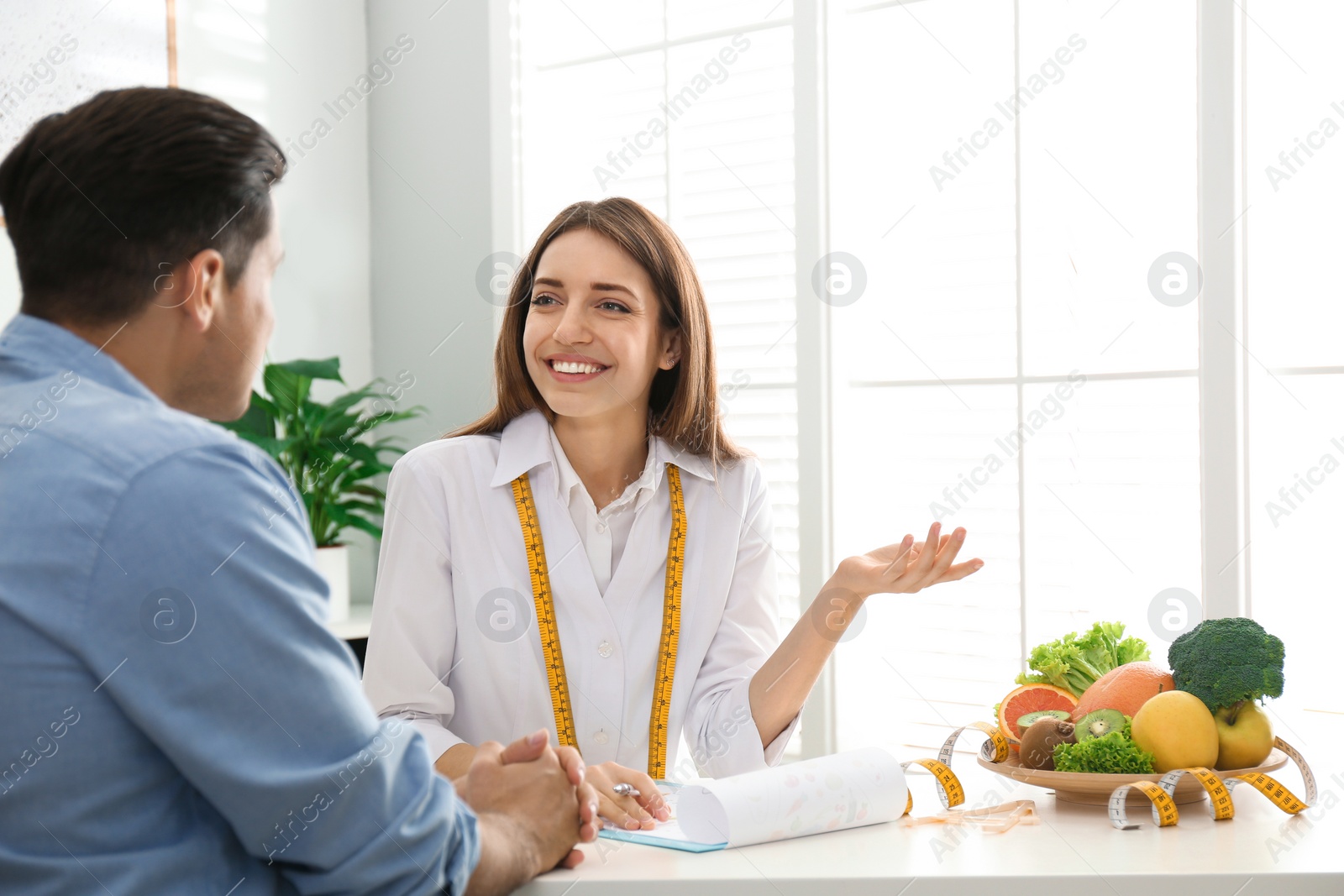 Photo of Young nutritionist consulting patient at table in clinic