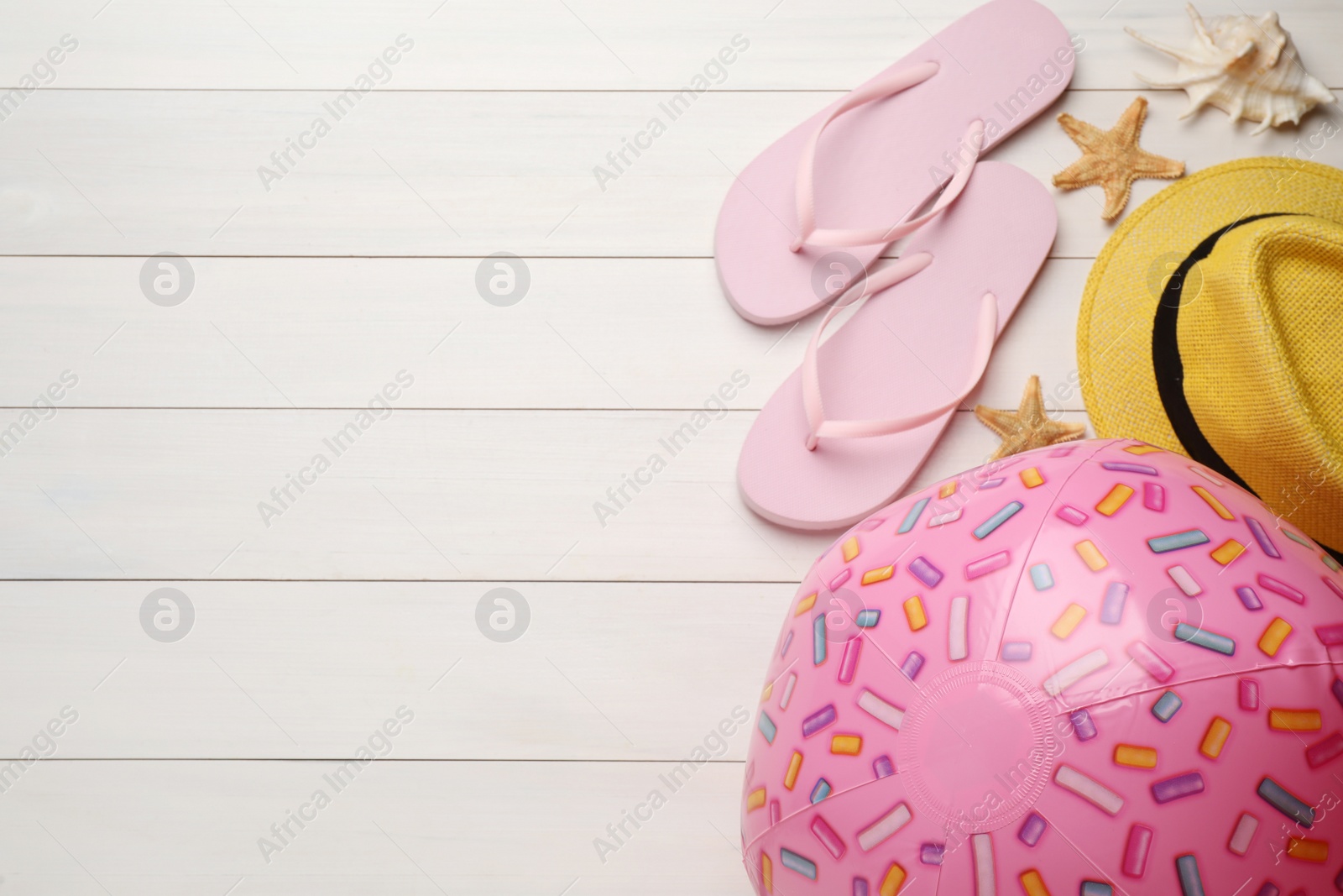 Photo of Pink beach ball, hat, seashell and flip flops on white wooden background, flat lay. Space for text