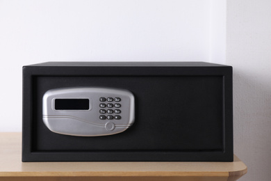 Photo of Black steel safe with electronic lock on wooden table