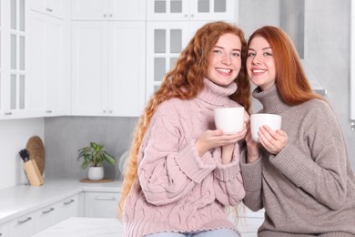 Photo of Portrait of beautiful young redhead sisters in kitchen. Space for text