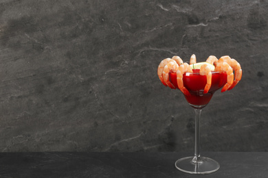 Photo of Delicious shrimp cocktail with tomato sauce served on black table. Space for text