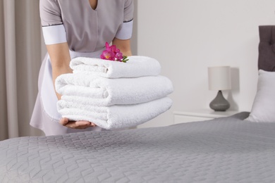 Maid putting fresh towels on bed in hotel room, closeup