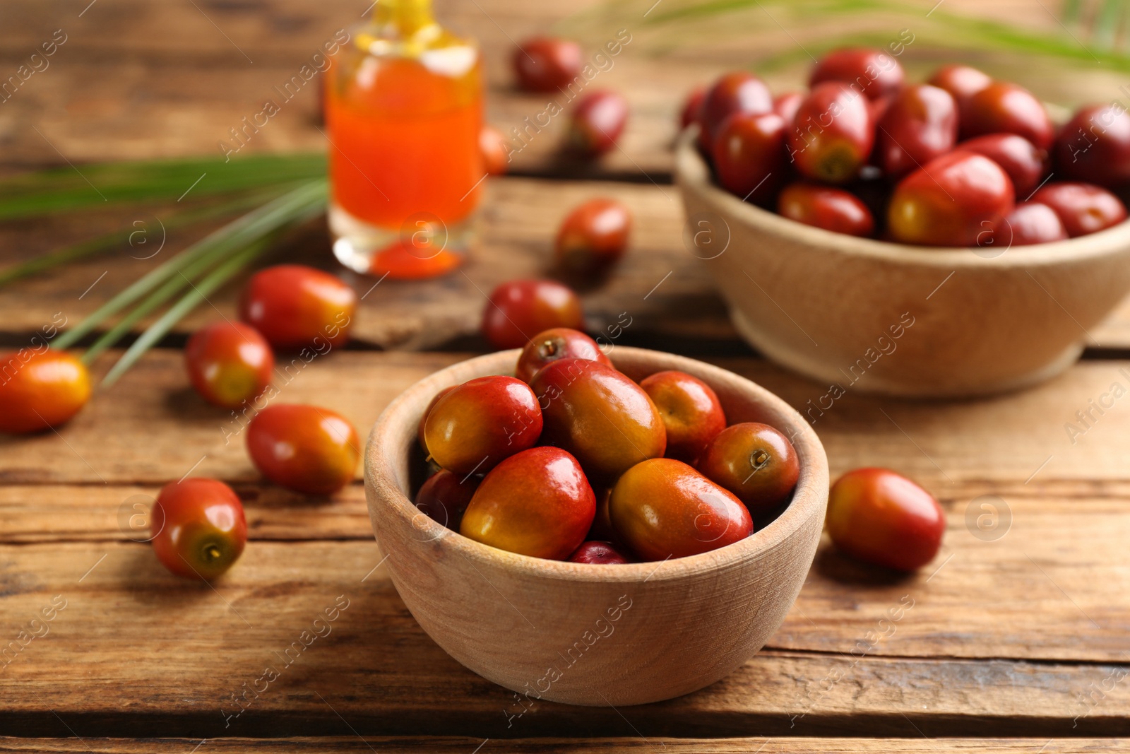 Photo of Palm oil fruits in bowl on wooden table, closeup