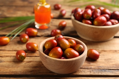 Palm oil fruits in bowl on wooden table, closeup