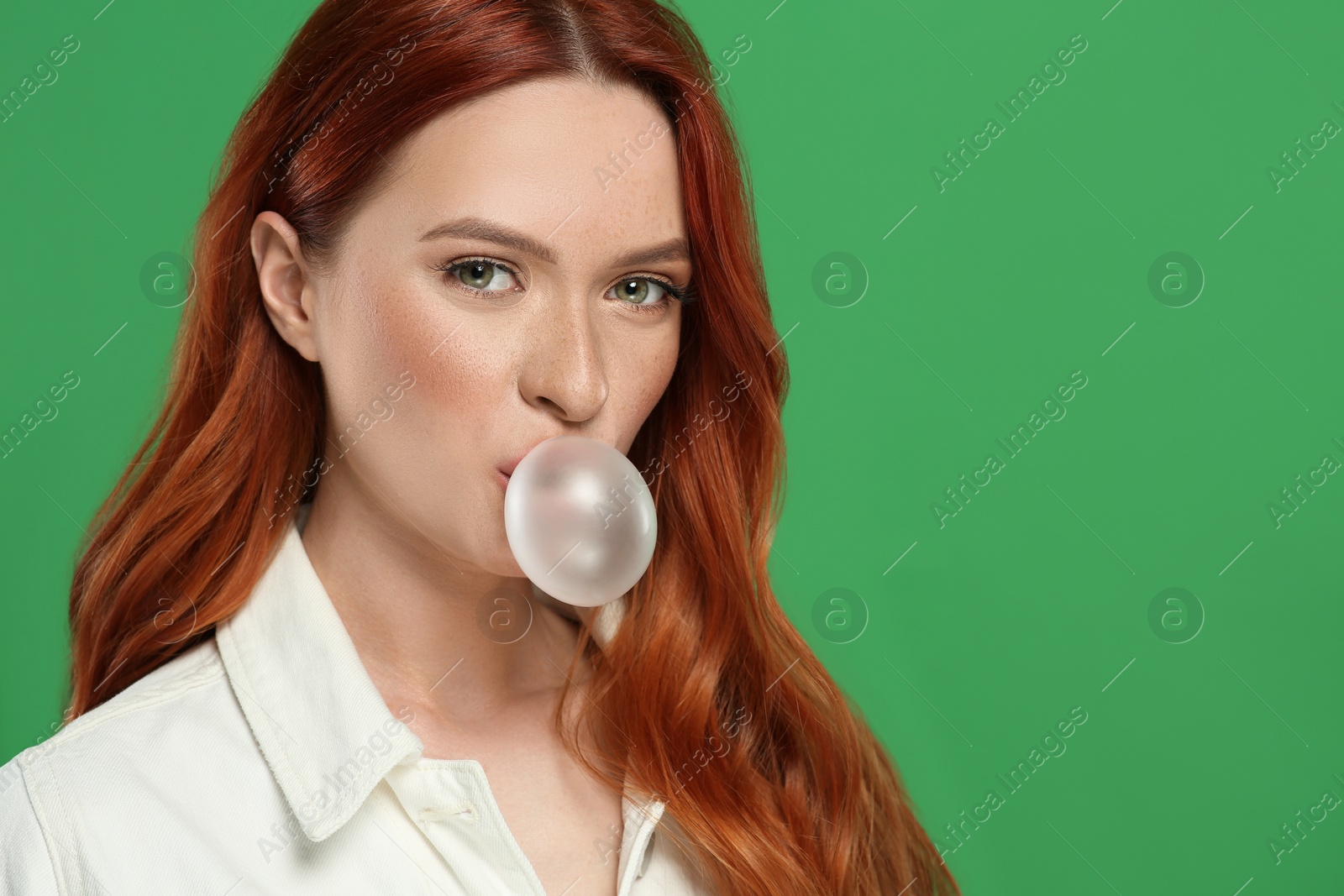 Photo of Beautiful woman blowing bubble gum on green background. Space for text