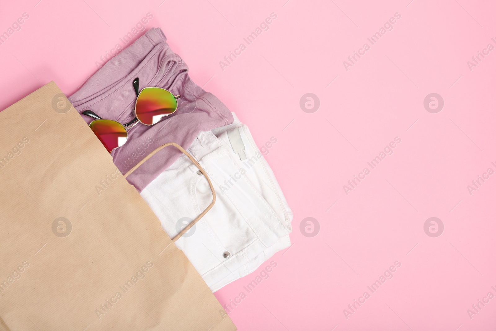 Photo of Stylish flat lay composition with shopping bag and clothing on color background