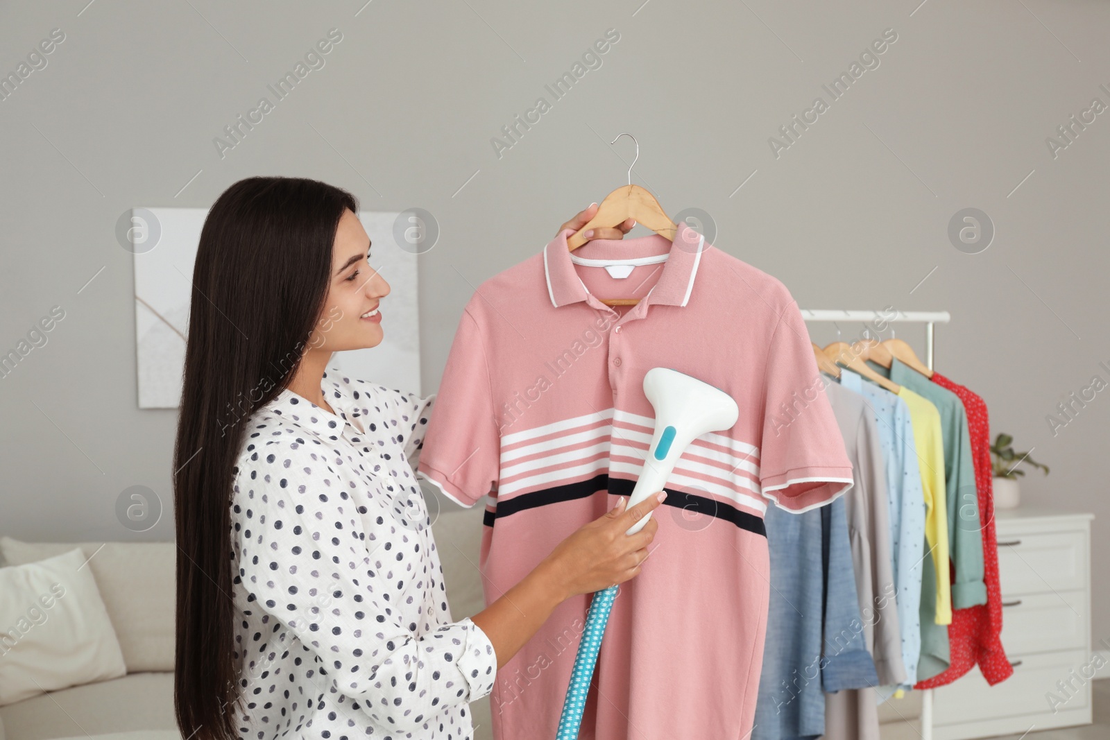 Photo of Woman steaming shirt on hanger at home