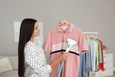 Woman steaming shirt on hanger at home