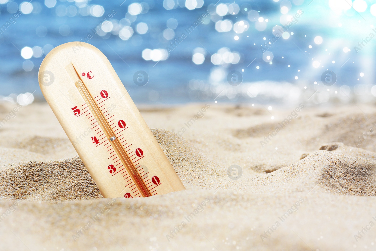 Image of Thermometer in sand on beach during sunny summer day