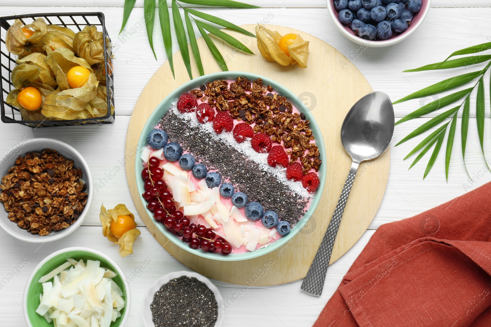 Photo of Tasty smoothie bowl with fresh berries and granola served on white wooden table, flat lay