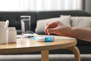 Photo of Woman with pills, organizer and glass of water at light wooden table, closeup