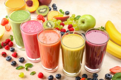 Photo of Fresh colorful fruit smoothies and ingredients on beige table
